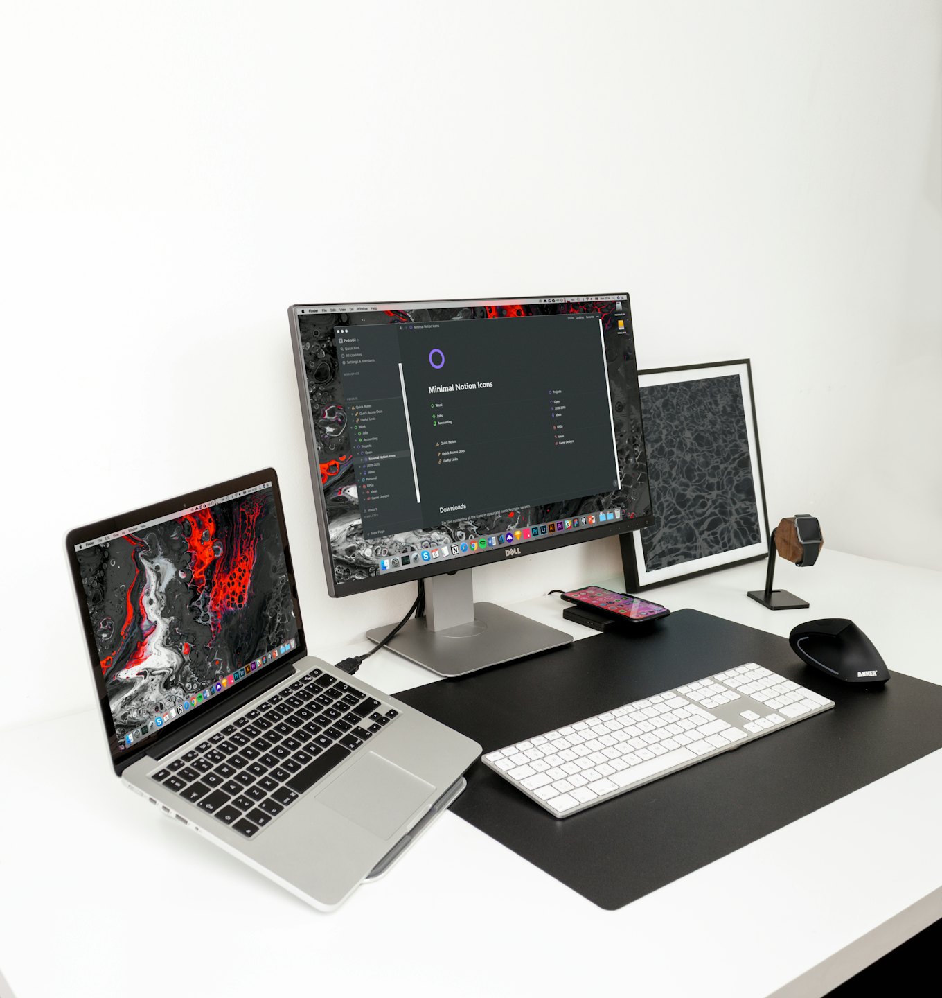 Minimalist workspace with a laptop, monitor, and desk accessories on a white desk.